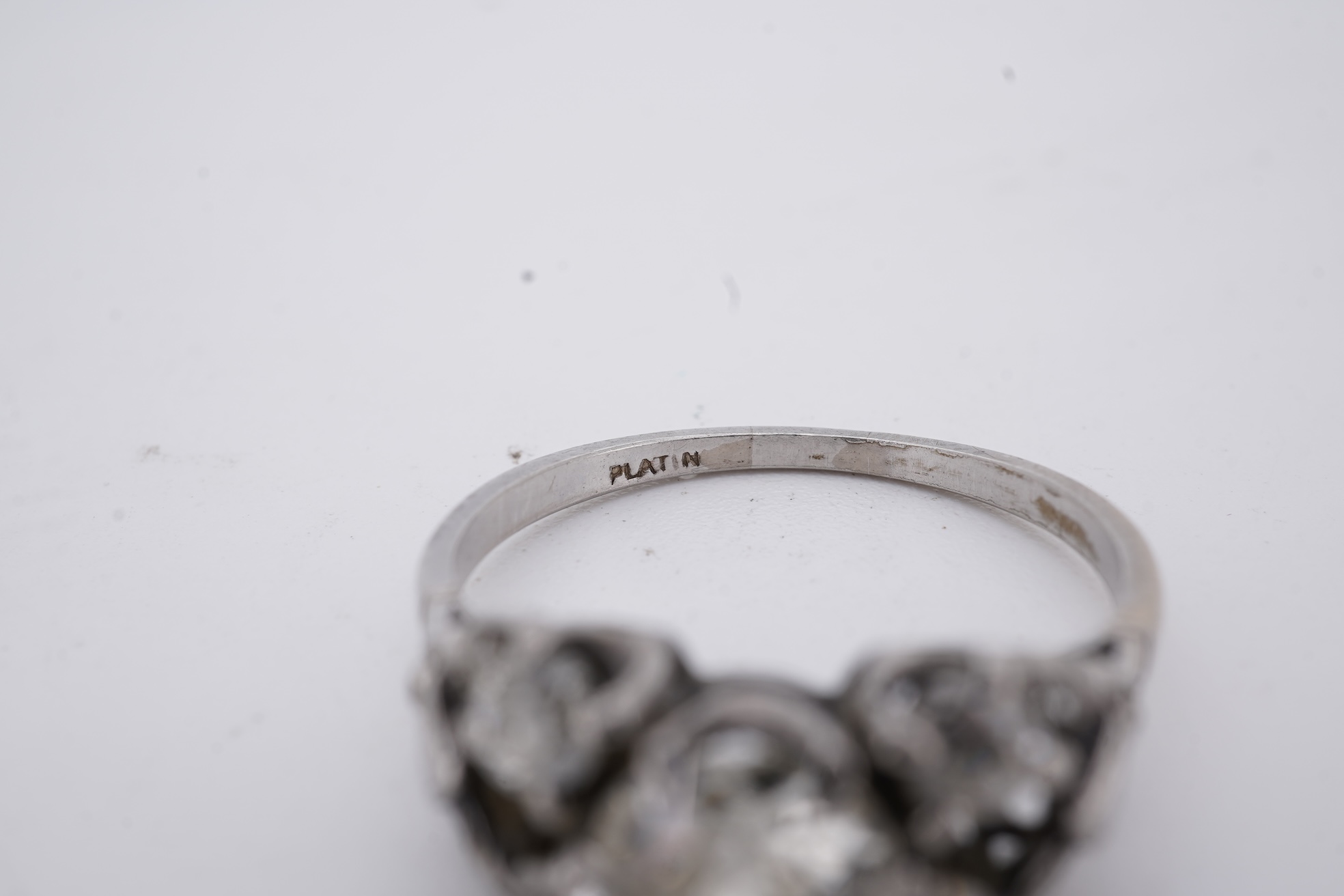 A white metal (stamped platin) and single stone diamond ring, flanked by four smaller diamonds and rose cut diamond chip set shoulders, size P, gross weight 3.8 grams.